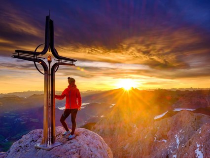 Mountaineer at the summit cross Hohe Goell at sunrise