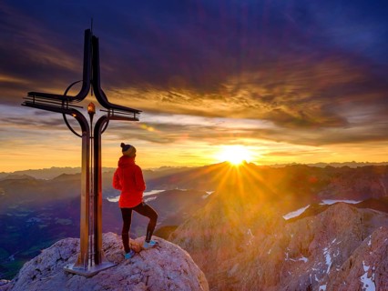 Mountaineer at the summit cross Hohe Goell at sunrise