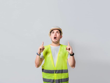 Amazed engineer pointing at an advertisement. Concept of an engineer with astonished face pointing at blank space