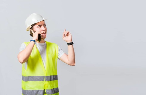Builder engineer in vest talking on cell phone isolated. Civil engineer concept talking on cellphone isolated