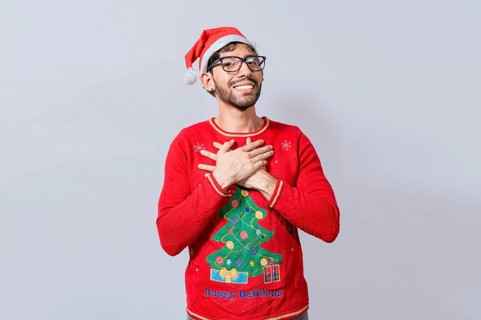 Thankful people in christmas clothes smiling with hands on chest. Man in christmas hat with sincere lovely smile feeling thankful