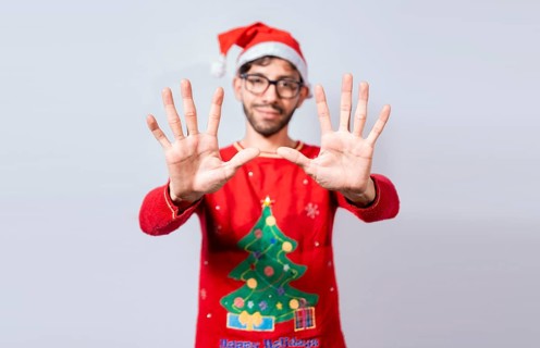 Man in christmas hat counting number ten with fingers. Christmas young man counting number ten with hands. Concept of man in christmas costume counting number ten isolated