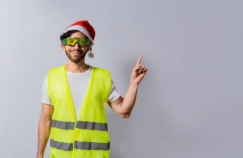 Builder worker with christmas hat pointing a finger at a promotion. Builder engineer in christmas hat pointing to the right