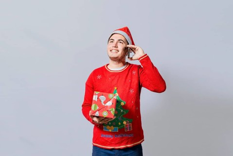 Happy guy holding gift and calling family at christmas