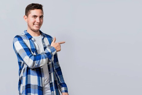 Smiling handsome man recommending something with his fingers. Caucasian handsome guy pointing his finger at a blank space