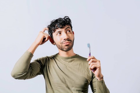 Thoughtful man holding toothbrush isolated