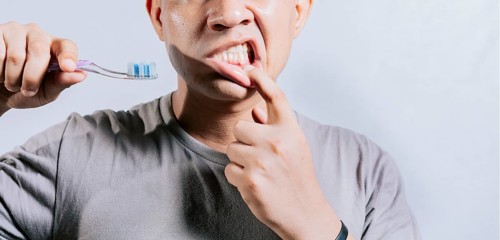 Person with gingivitis holding toothbrush. People holding toothbrush with gum pain. Man holding toothbrush with gum pain