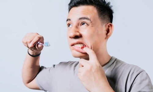 Man holding toothbrush with gum pain isolated