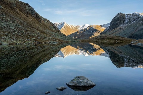 Slightly snow-covered mountains reflected in Schwarzsee in autumn on the Flueela Pass