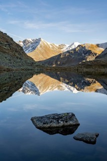 Slightly snow-covered mountains reflected in Schwarzsee in autumn on the Flueela Pass
