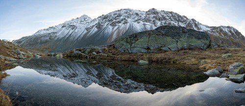 Lightly snow-covered mountains and mountain lake in autumn on the Flueela Pass