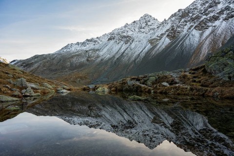 Lightly snow-covered mountains and mountain lake in autumn on the Flueela Pass