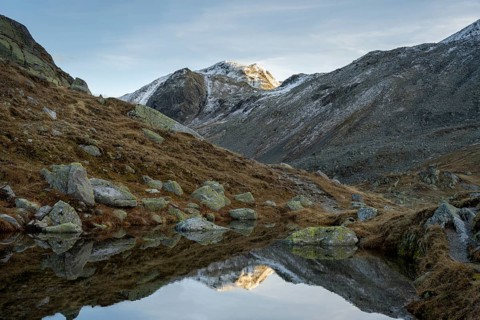 Lightly snow-covered mountains and mountain lake in autumn on the Flueela Pass