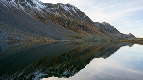 Slightly snow-covered mountains reflected in Lake Schotten in autumn at the Flueela Pass