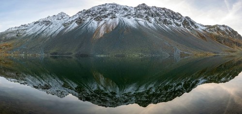 Slightly snow-covered mountains reflected in Lake Schotten in autumn at the Flueela Pass