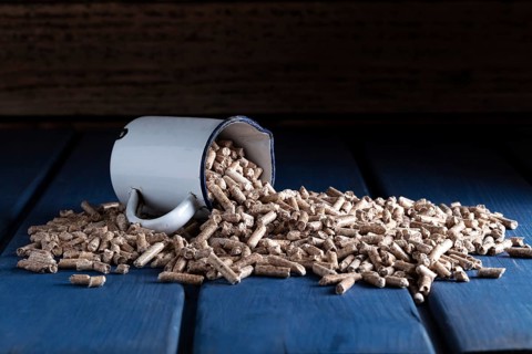 Wood pellets with enamel cup on blue wooden background