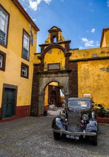 Vintage car parked in front of yellow gate and wall