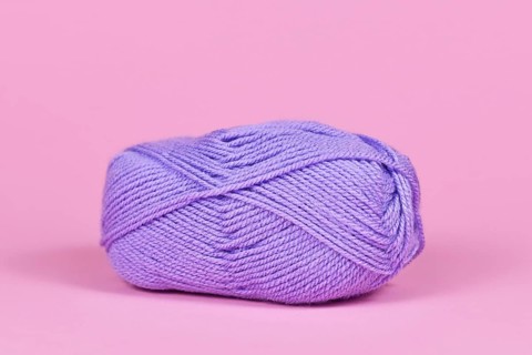 Single violet ball of wool on pink background