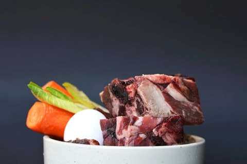 Dog or cat bowl filled with mixture of biologically appropriate raw food containing of meat chunks