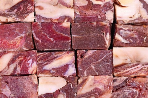 Big chunks of streaked red raw horse meat with lots of fat used for raw feeding of dogs or cats