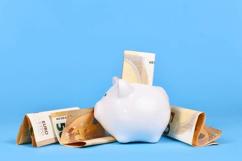 Saving money concept. White piggy bank with 50 Euro bills on blue background