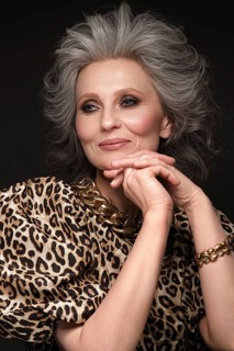 Portrait of a beautiful elderly woman in a leopard blouse with classic makeup and gray hair