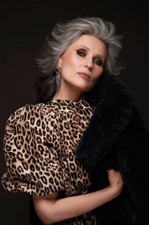Portrait of a beautiful elderly woman in a leopard blouse and fur coat with classic makeup and gray hair