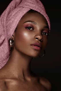 Beautiful black woman with a pink towel on her head and classic makeup. Beauty face. Photo taken in the studio