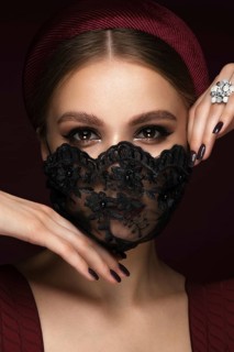 Portrait of a beautiful woman in a black lace mask and classic makeup. Mask mode during the covid pandemic