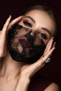 Portrait of a beautiful woman in a black lace mask and classic makeup. Mask mode during the covid pandemic