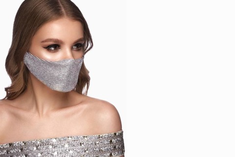 Portrait of a beautiful woman in a silver mask with rhinestones and classic makeup. Mask mode during the covid pandemic
