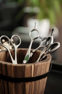 Hairdressing tools scissors close-up in a wooden vase. Close up