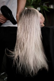 Young woman in a hairdressing salon dyes her hair blond and dries hair