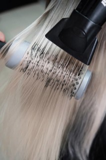 Young woman in a hairdressing salon dyes her hair blond and dries hair
