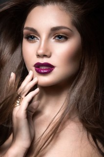 Beautiful girl with golden makeup and burgundy lips with the wind in hair. Beauty face. Picture taken in the studio on a black background