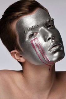 Young man with art creative art make-up with silver paint on his face. Beauty face. Picture taken in the studio on a white background