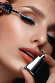 Beautiful girl with sexy lips and classic makeup with cosmetic blue eyeliner in hand. Beauty face. Photo taken in the studio