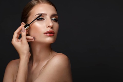 Beautiful girl with sexy lips and classic makeup with cosmetic mascara brush in hand. Beauty face. Photo taken in the studio
