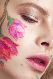 Beautiful blond girl with tresses and a floral pattern on the face. Beauty flowers. Portrait shot in studio