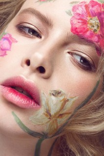 Beautiful blond girl with tresses and a floral pattern on the face. Beauty flowers. Portrait shot in studio