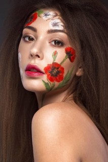 Beautiful brunette girl with curls and a floral pattern on the face. Beauty flowers. Portrait shot in studio