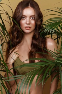 Beautiful sexy woman in a bikini posing in the middle of green plants. Summer look. Beauty face. Photo taken in the studio