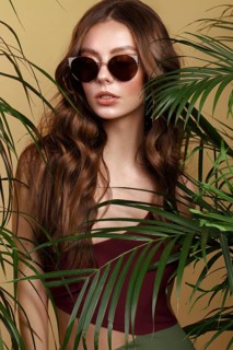 Beautiful sexy woman in a bikini and sunglasses posing in the middle of green plants. Summer look. Beauty face. Photo taken in the studio