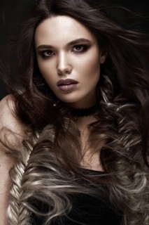 Brunette girl with a creative hairstyle braids and dark make-up. Beauty face. Photo taken in the studio
