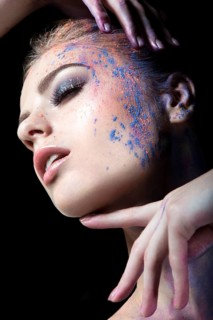 Portrait of a beautiful Girl with red paint on her face. Photo shot in the Studio on a black background