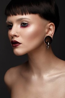 A beautiful girl with art creative make-up and earrings on the face. Photos shot in studio