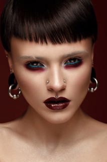 A beautiful girl with art creative make-up and earrings on the face. Photos shot in studio
