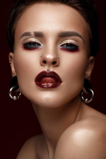 A beautiful girl with art creative make-up and earrings on the face. Photos shot in studio