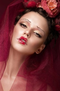 Beautiful girl with art creative make-up in the image of a red bride for Halloween. Beauty face. Photo taken in studio