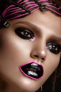 A beautiful girl with a black creative make-up and a pink thread on her lips. Beauty face. Photos shot in studio
